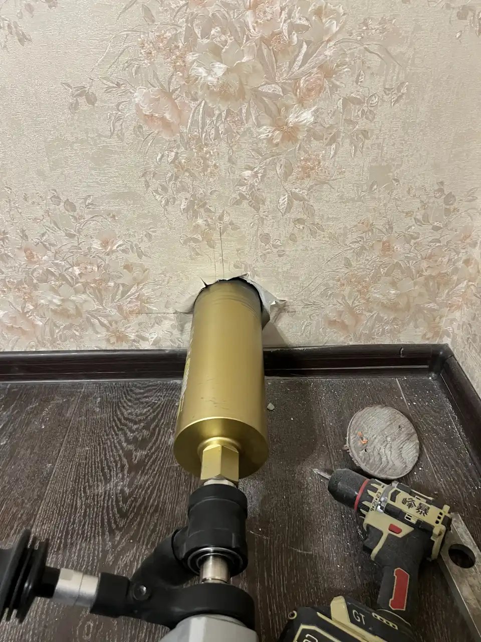 Алмазная коронка дрели в стене с обоями